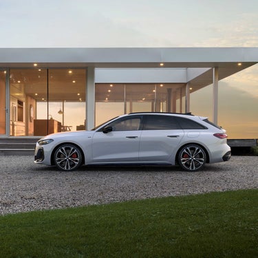 Audi A5 Avant e-hybrid im Profil steht vor einem gläsernen Wohnhaus