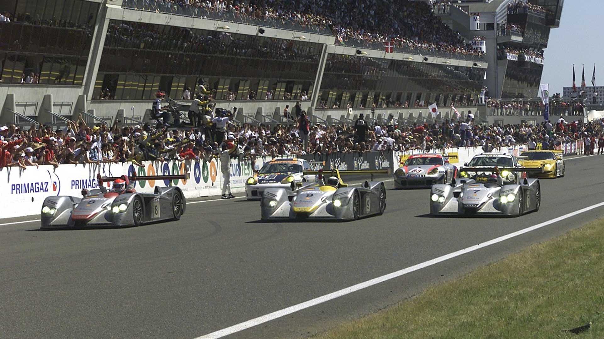 A picture of the three Audi R8 race cars crossing the finish line at Le Mans in 2000.