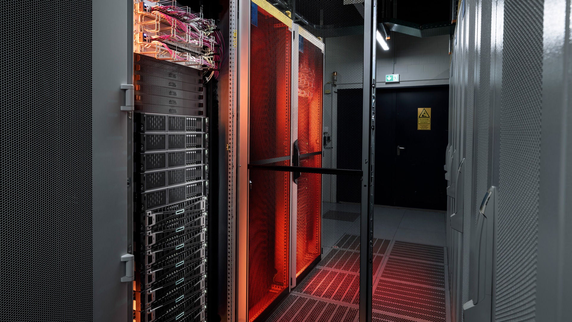 Orange-lit edge cloud servers in metal cabinets with perforated mesh doors.