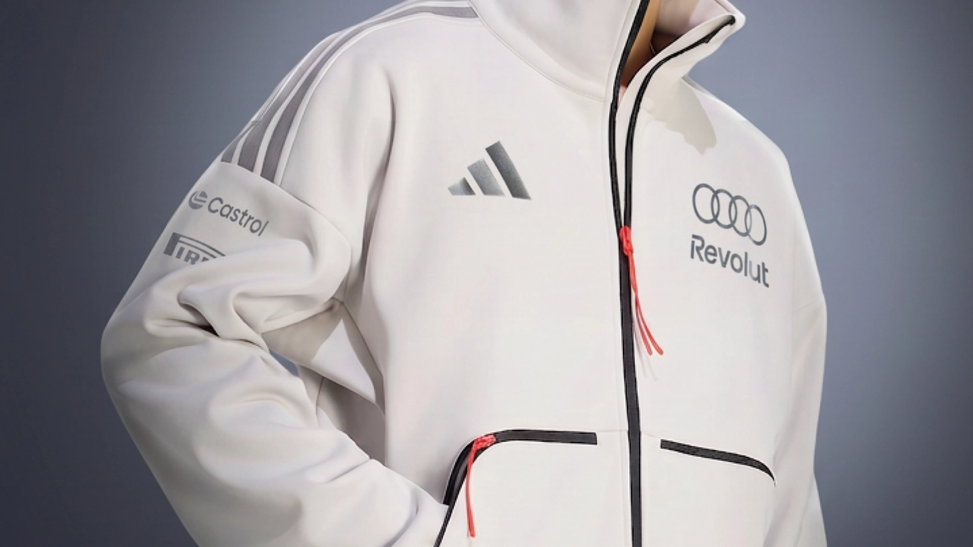 Person wearing an off-white Adidas jacket featuring Audi, Revolut, Castrol, and Pirelli sponsor logos
