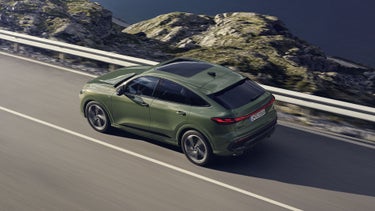 Der Q5 Sportback im schrägen Seitenprofil von oben betrachtet. Das Fahrzeug fährt auf einer Gebirgsstraße.