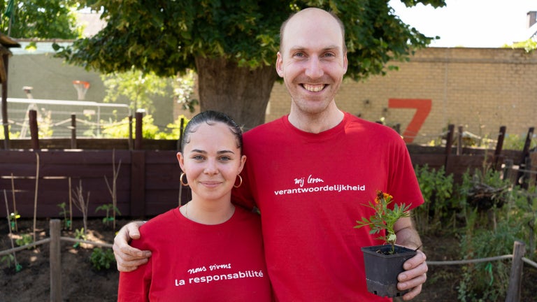 Two employees wearing red Audi Social Day T-shirts smile for the camera.