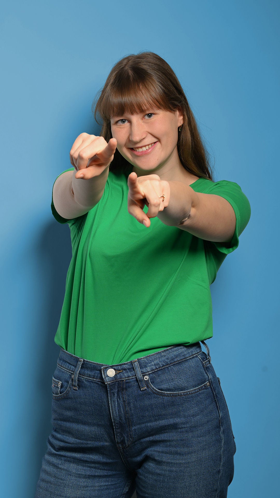 Josee zeigt auf die Kamera mit beiden Händen