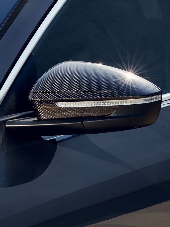 Nahaufnahme eines Seitenspiegels aus Carbonoptik mit integriertem Blinker an einem grauen Audi Q5 SUV.