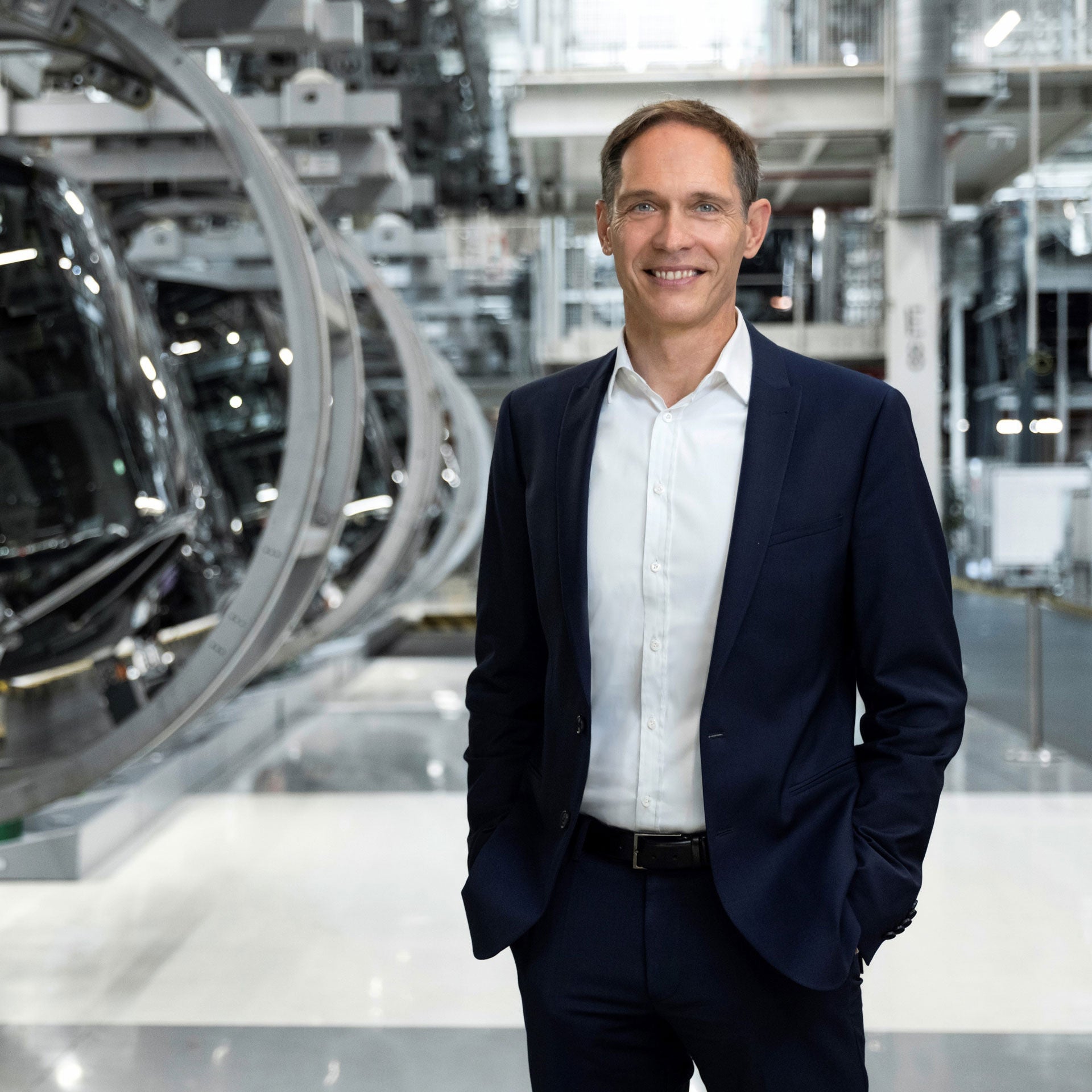 Gerd Walker stands smiling cheerfully in a production hall.