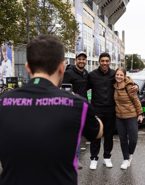 Ein Mann macht BIlder von einer Gruppe vor dem Fahrzeug