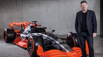 Bild på Gernot Döllner bredvid en F1 bil.