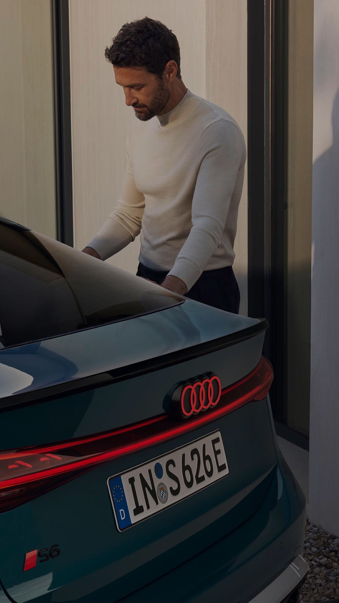 Deep green Audi charging outside gated property