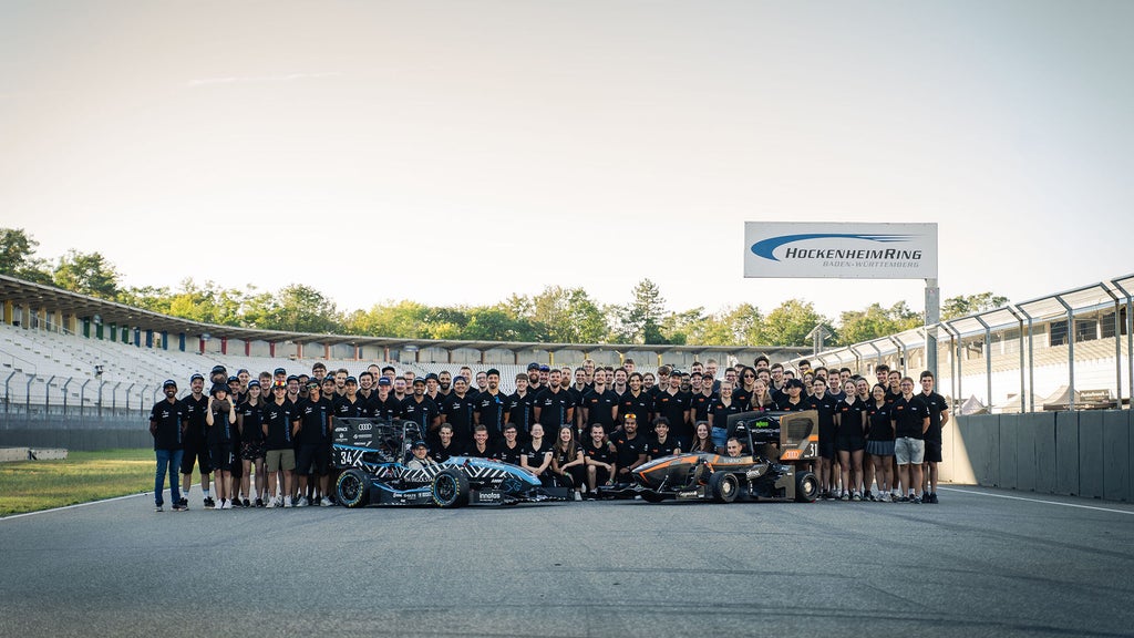 Gruppenfoto des Teams TUfast e.V. und Schanzer Racing e.V. mit ihren Fahrzeugen am Hockenheimring