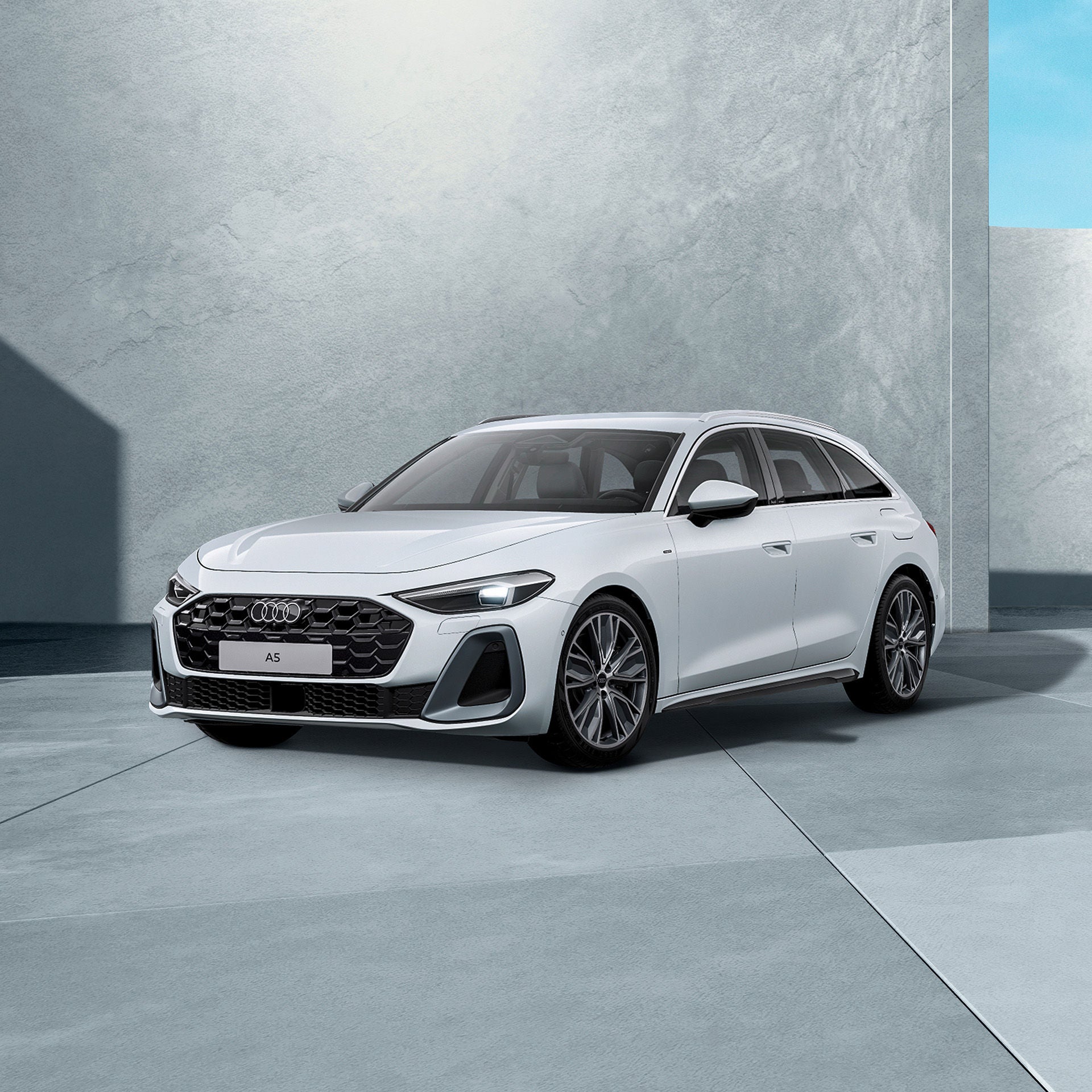 Ein weißer Audi A5 Avant e-hybrid von schräg vorne fotografiert vor einer modernen Kulisse.