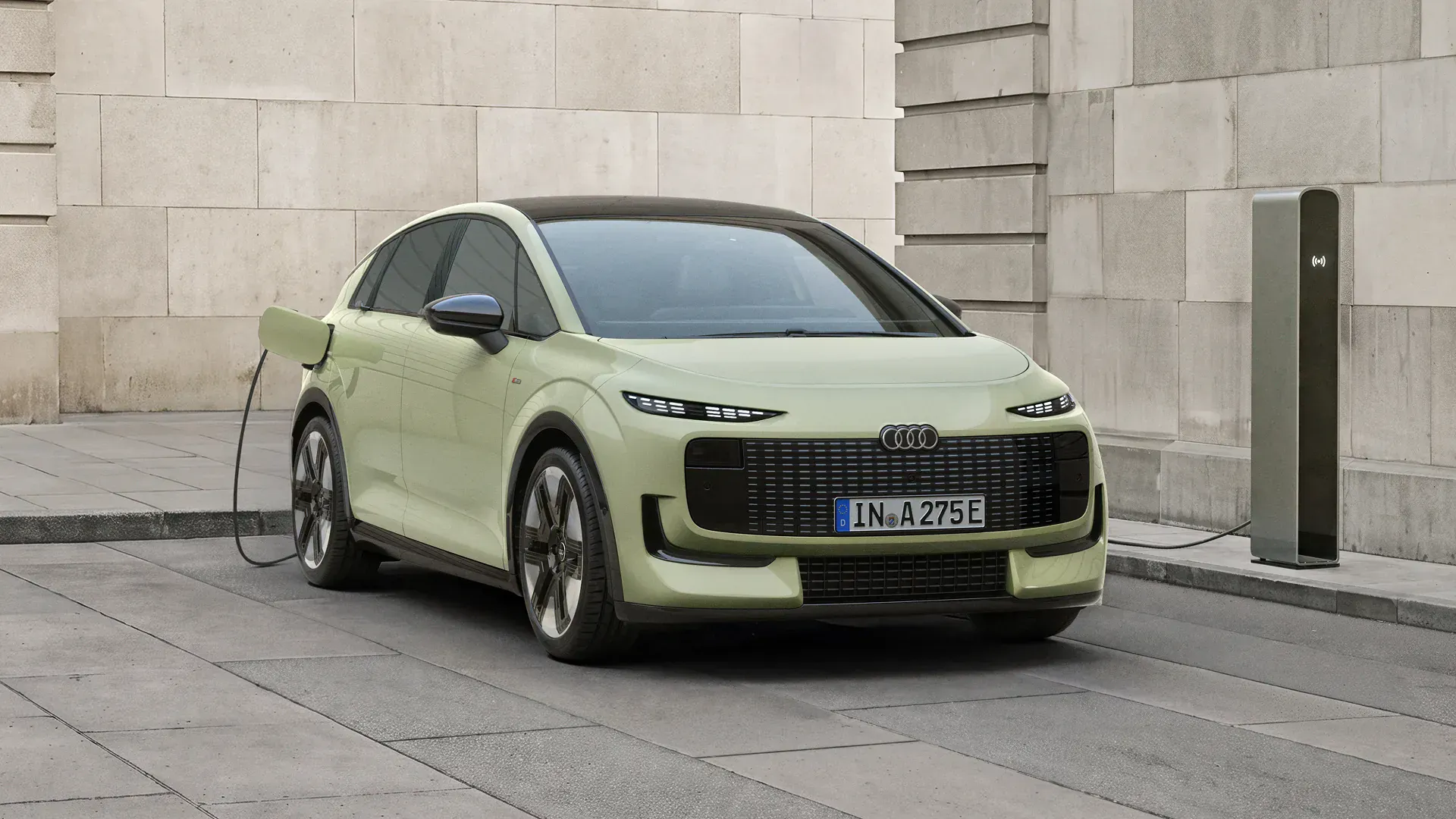 Pistachio green Audi A2 e-tron electric hatchback plugged into a charging station on a clean street