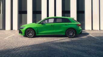 Een groene Audi RS 3 Sportback staat voor een gebouw