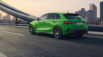 Der RS 3 Sportback von schräg hinten überquert eine Brücke, im Hintergrund Wolkenkratzer.