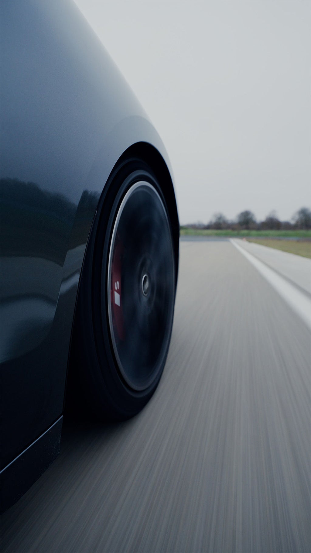 Detailansicht eines Audi S6 Avant e-tron Vorderreifens in Fahrt auf Asphalt.