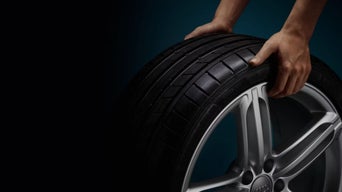 Cropped shot of an Audi wheel with rim being rolled by a pair of hands.