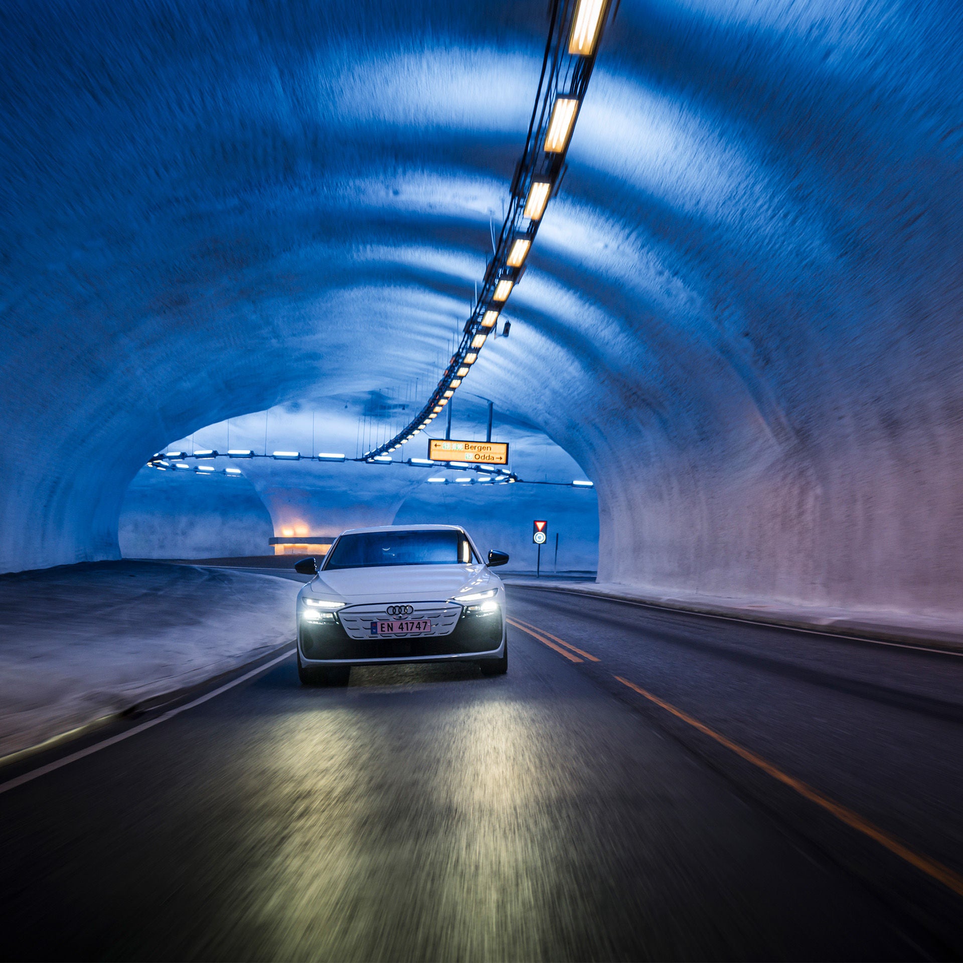 The white A6 Sportback e-tron performance is bathed in blue light by the ceiling lighting of the Vallavik Tunnel.