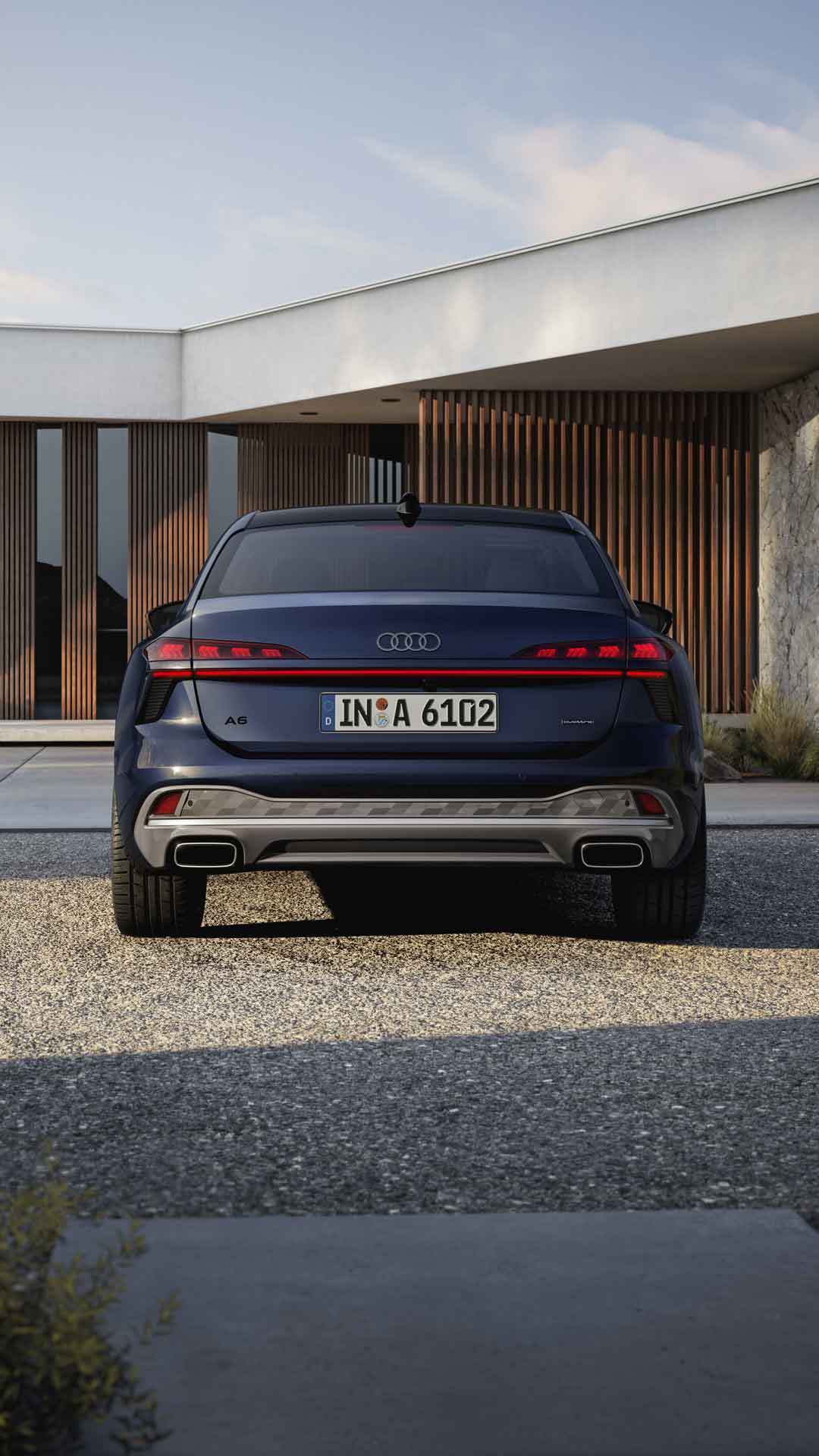 Die A6 Limousine in der Heckperspektive. Das Fahrzeug steht einem modernen Haus zugewandt.