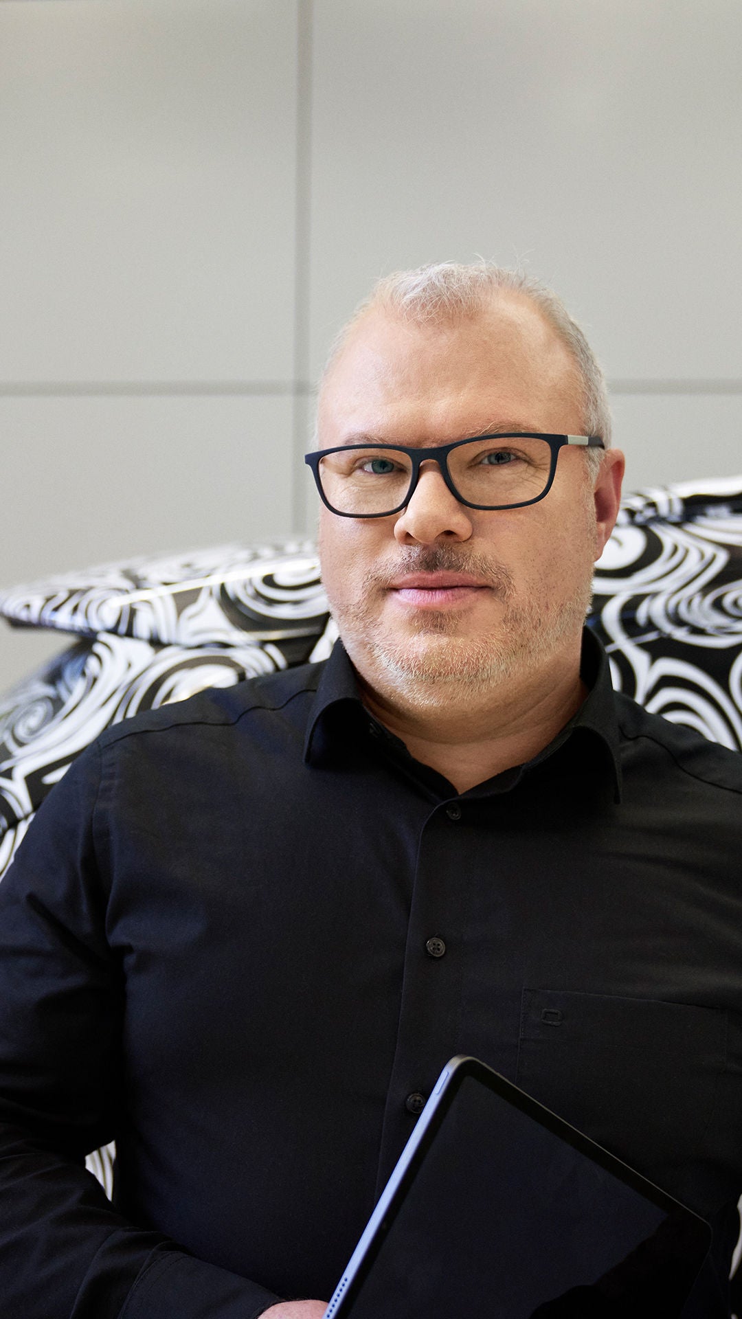 Steffen schaut in die Kamera und steht vor einem schwarz weißen Audi mit Muster