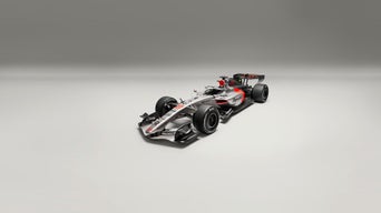 Schrägansicht eines silber-schwarzen Formel-1-Rennwagens mit roten Akzenten vor grauem Hintergrund.