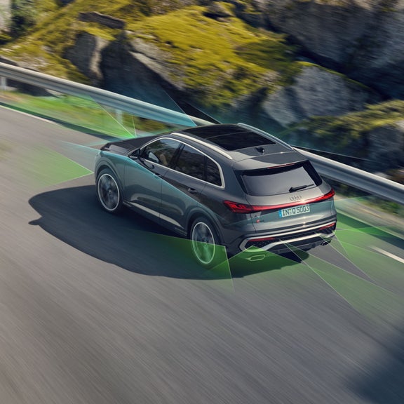 A grey Audi SUV with active safety features displayed via green overlays.