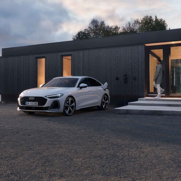 Audi A5 Berline e-hybrid tijdens het opladen terwijl een man zijn huis verlaat