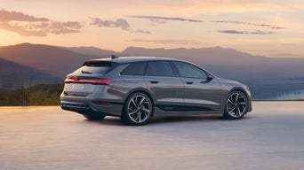 A gray Audi Avant e-tron side view while parked with mountains in the background