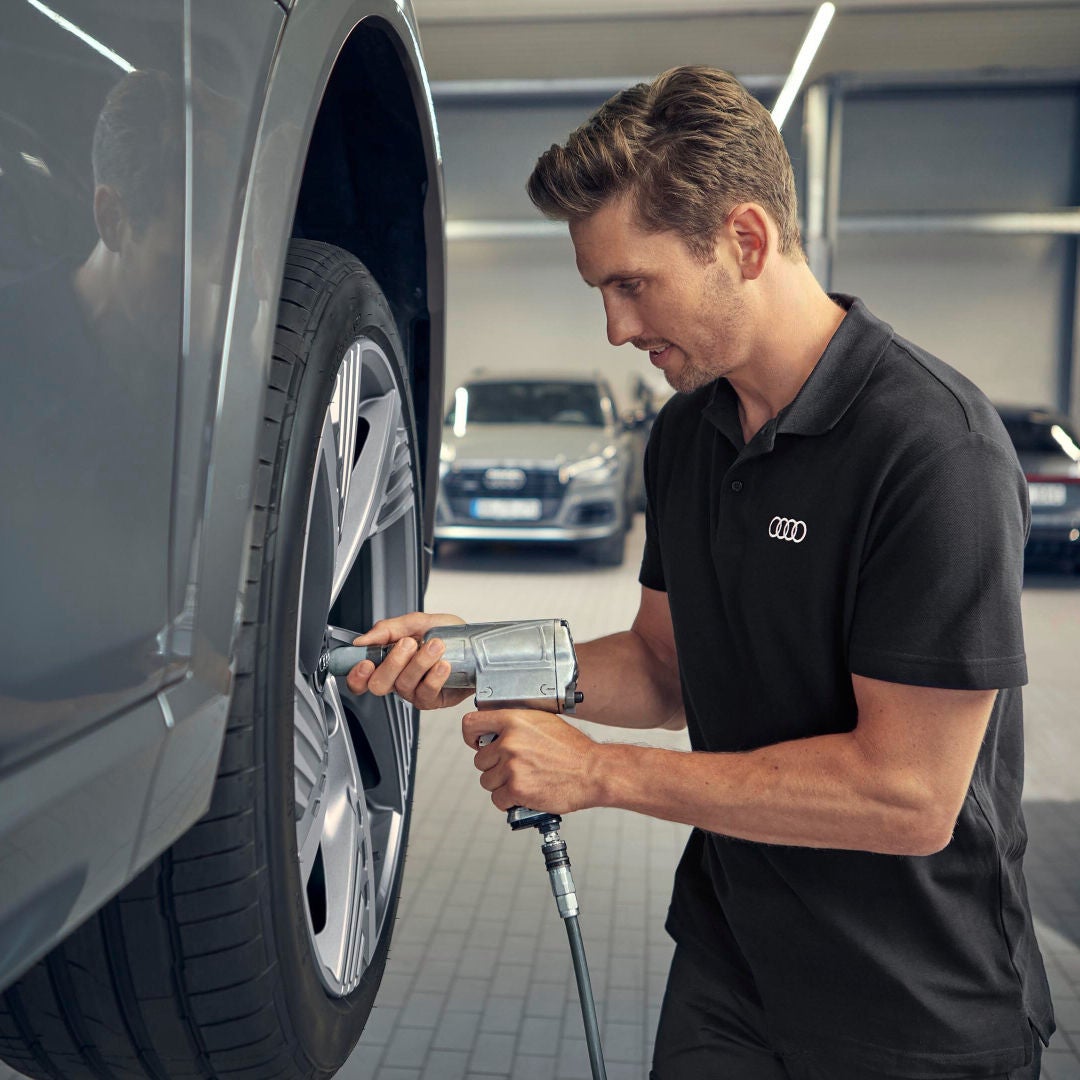 In officina un tecnico utilizza un avvitatore pneumatico per lavorare sulla ruota di un veicolo Audi.