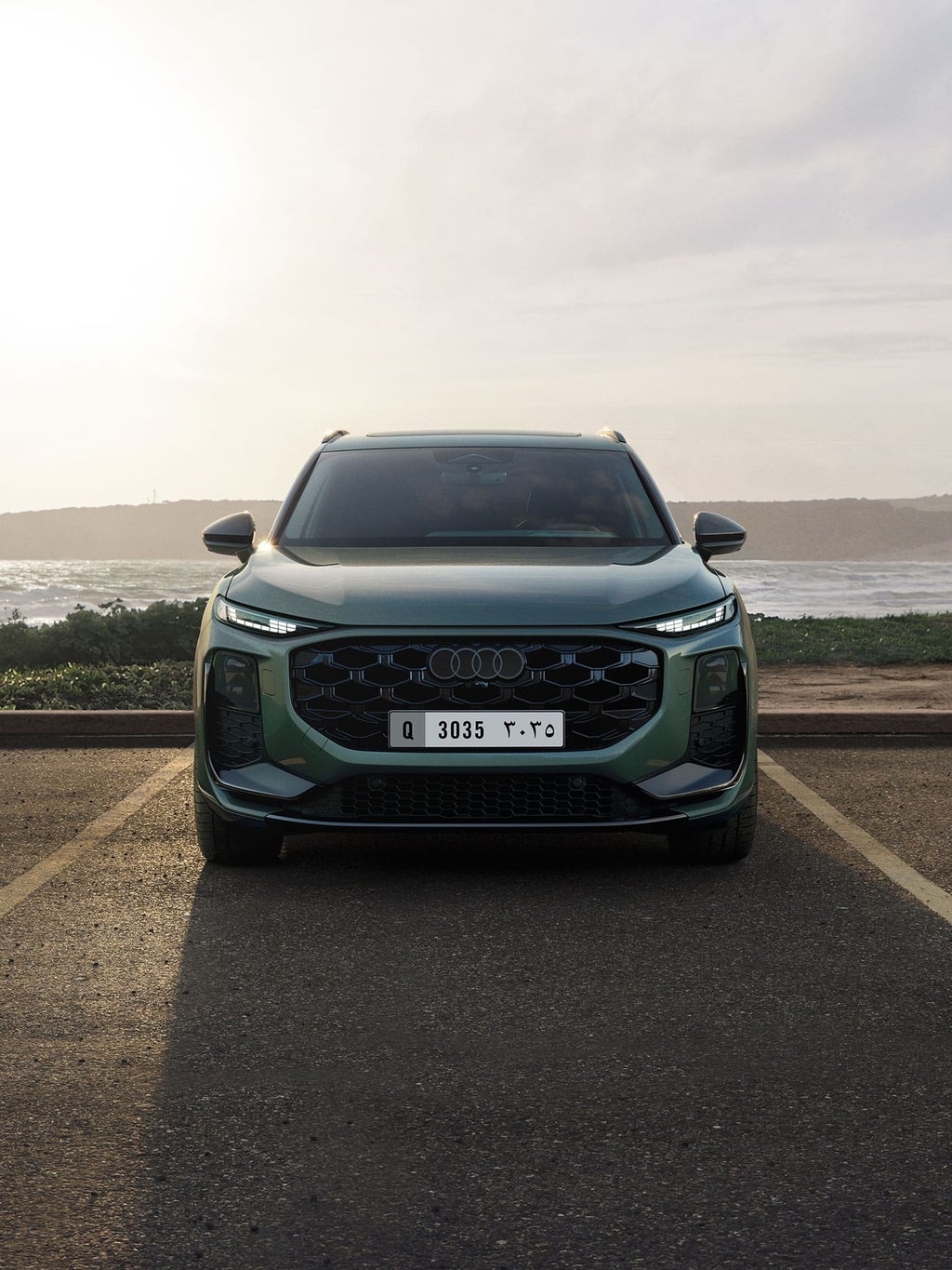 Audi Q3 SUV front view, parking in front of the water.