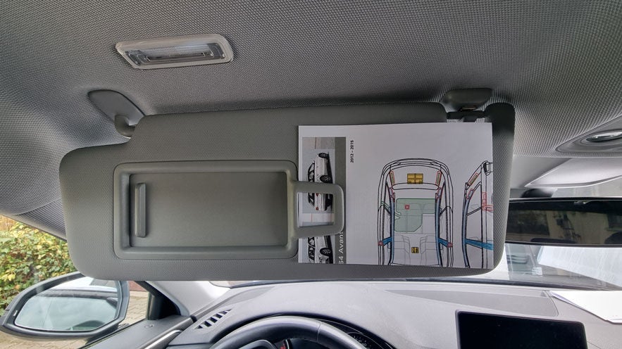 Ein Rettungsdatenblatt steckt hinter der Sonnenblende eines Autos, sichtbar von der Fahrerseite aus fotografiert.