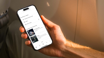 A person holding a smartphone displaying the myAudi app with vehicle details and customisation options