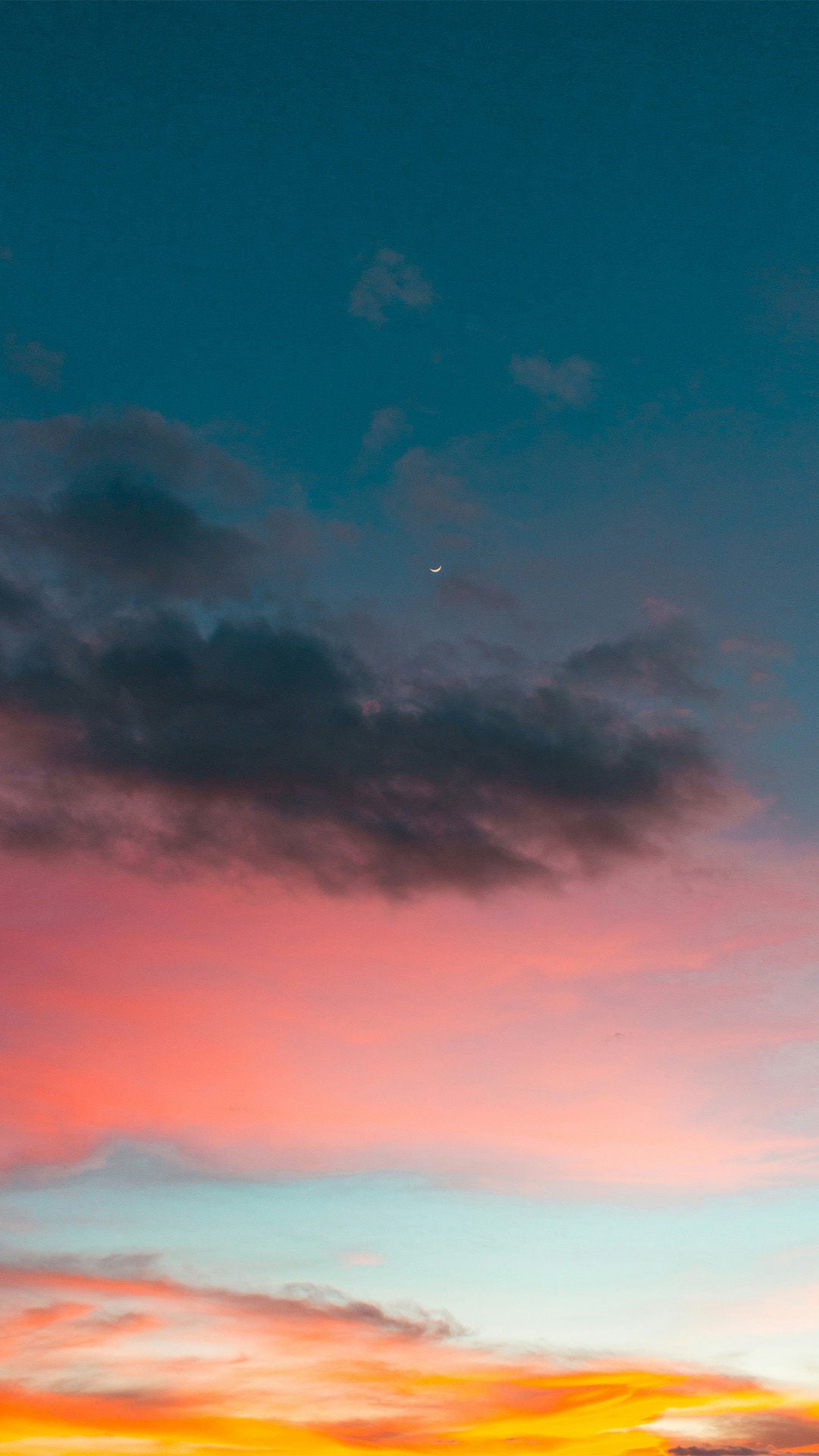 Abendhimmel mit farbigem Sonnenuntergang in Orange, Rosa und Türkis sowie dunklen Wolken und einer schmalen Mondsichel.