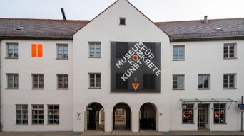 Fassade des Museums für Konkrete Kunst mit großem schwarzem Schriftbanner über dem Eingang.