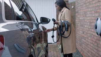 A young woman placing a charger cable in to her Audi electric vehicle