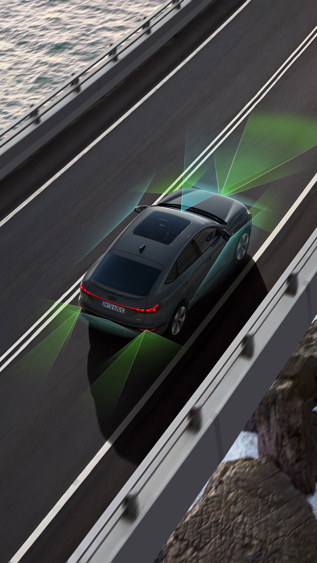 Vogelperspektive eines Audi Q6 e-tron, der über eine Brücke fährt. Unter ihm sind Wasser und Felsen. Um den Q6 herum sind grafisch Sensoren angedeutet, die die Fahrerassistenzsysteme symbolisieren.