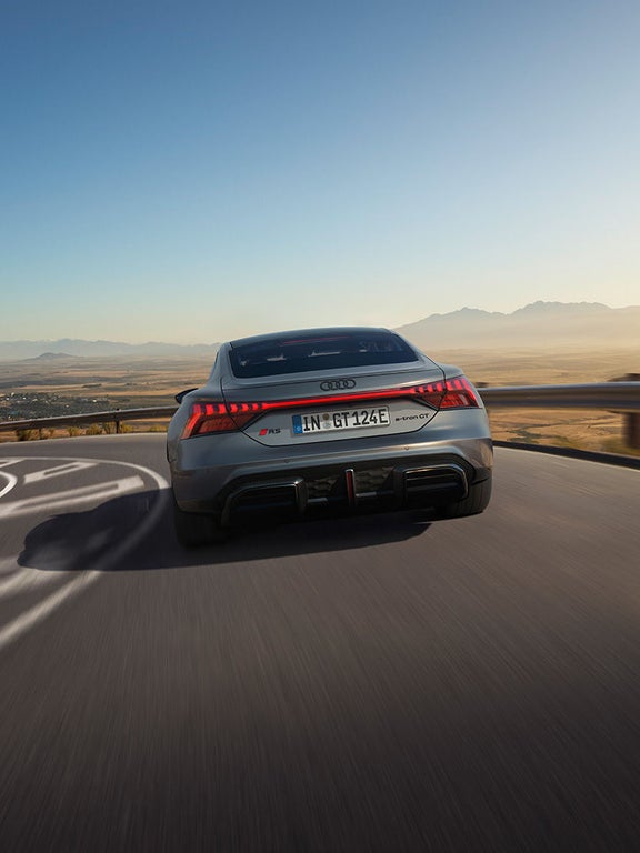 Der Audi RS e-tron GT fährt auf einer kurvigen Straße mit Panorama-Ausblick auf eine weite Landschaft.
