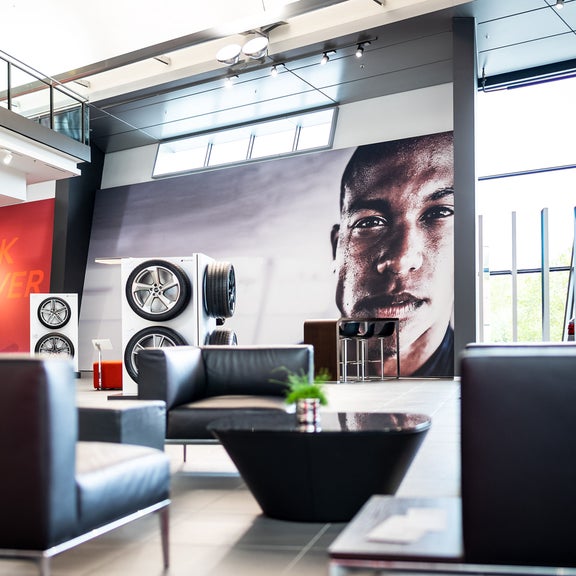 Black leather armchairs and tables in front of a large mural of a face, tire presentation in the background.