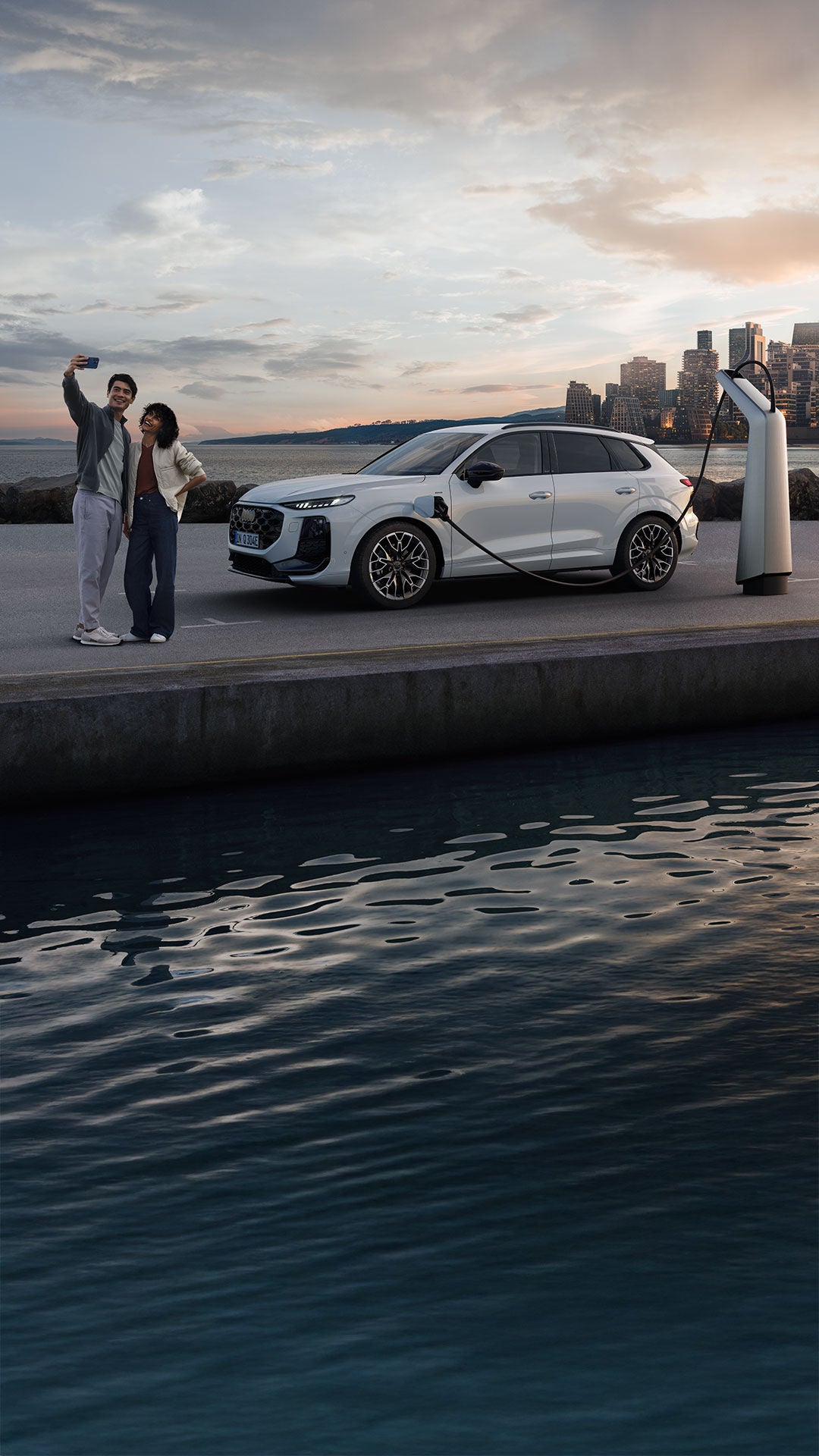 Vista laterale di Audi Q3 SUV e-hybrid di ricarica in un parcheggio