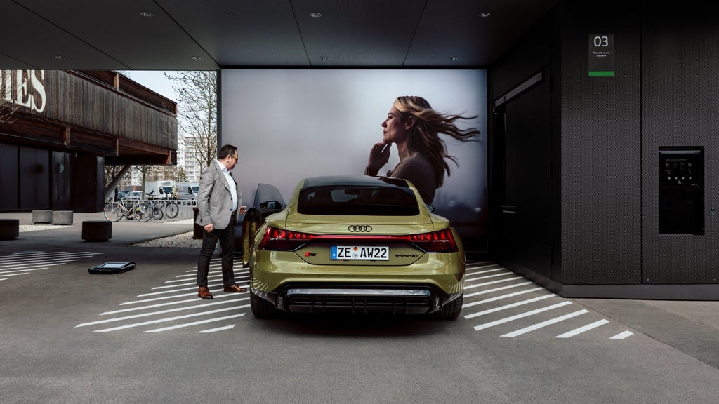 Helmuth Brants se tient à côté de l'Audi RS e-tron GT devant un grand écran.