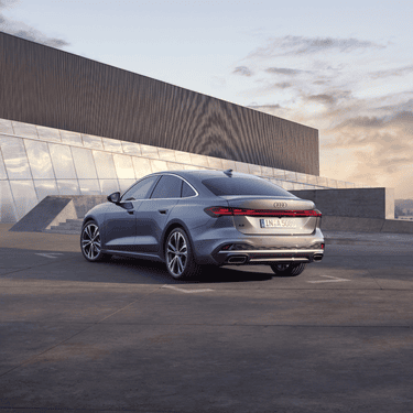 Silver Audi A5 Saloon parked outside a modern building at dusk.
