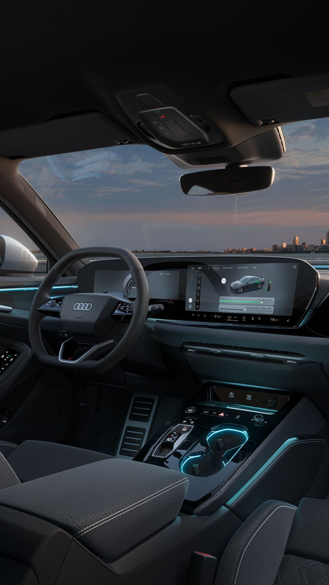 Blick von der Rückbank in das Cockpit der A5 Limousine e-hybrid. Zu sehen sind unter anderem die MMI touch-Displays, sowie die Ambientebeleuchtung und das Interaktionslicht. Im Hintergrund ist die Skyline einer Stadt zu sehen.