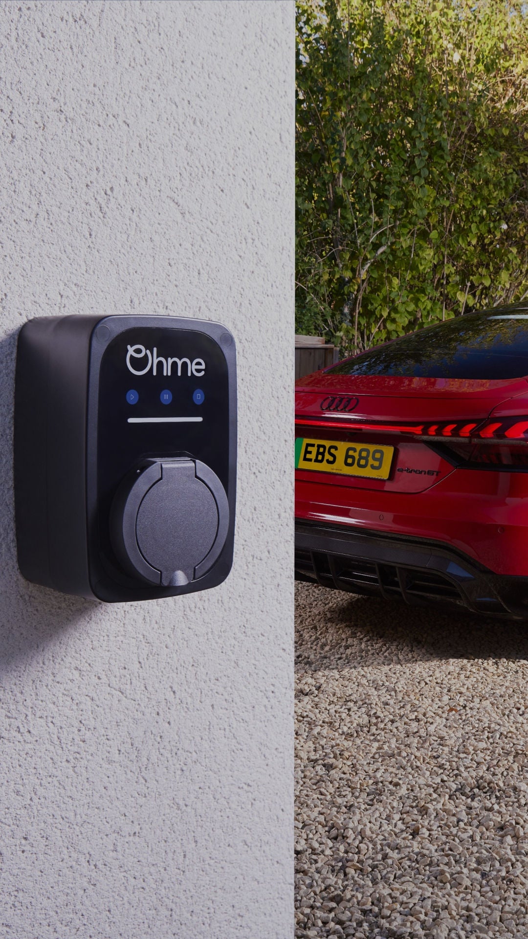 An Ohme charge point on a wall with a parked red Audi electric vehicle in the background
