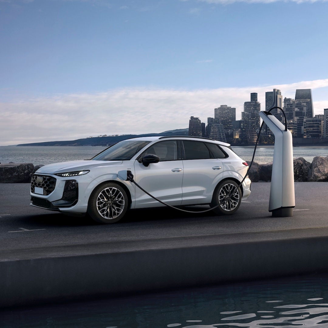 Audi Q3 e-hybrid parcheggiata e collegata a una colonnina di ricarica