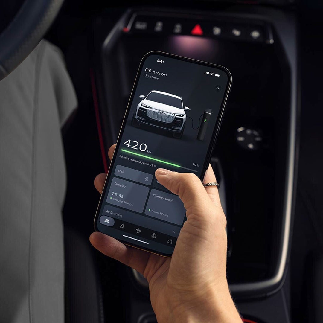 Hand holding up a mobile phone with myAudi app visible on its screen