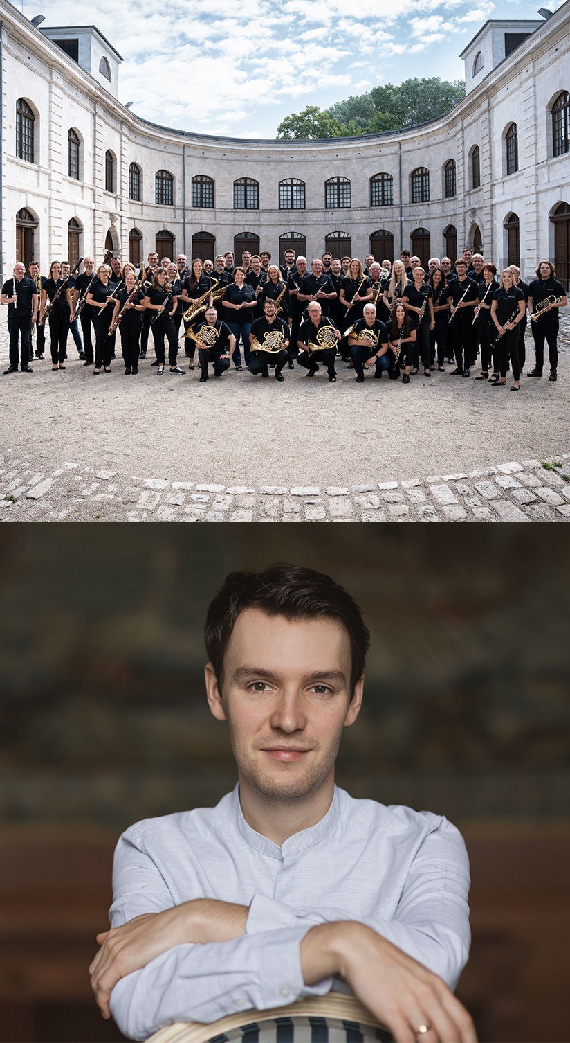 Die Audi Bläserphilharmonie steht mit Instrumenten im Innenhof eines Rundbaus; rechts ein Porträt eines jungen Mannes mit hellem Hemd.