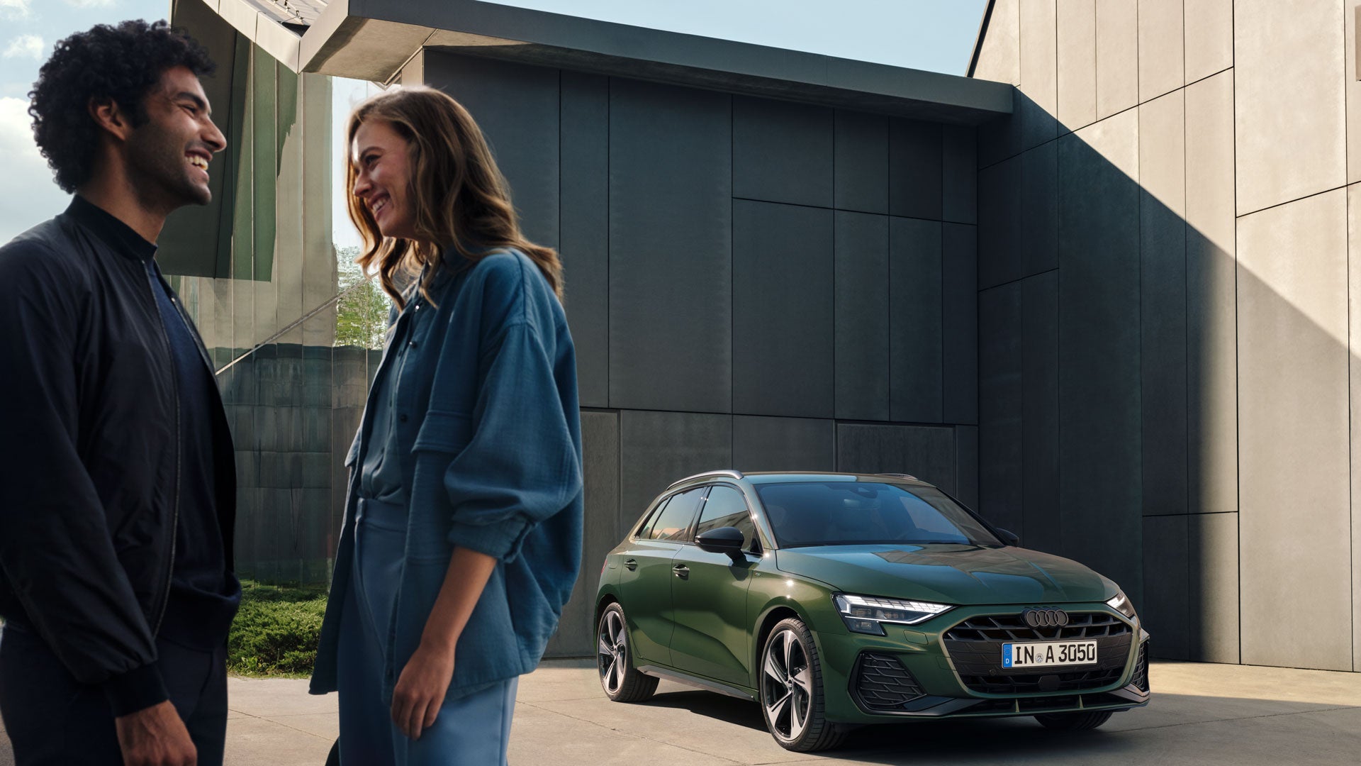 Ein Mann und eine Frau unterhalten sich vor einem grünen Audi A3.
