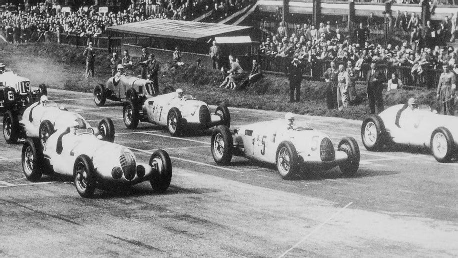 En svartvit bild på ett race med Auto Union Type C, designad av Ferdinand Porsche, känns igen på sin mittmotordesign med motorn bakom föraren.