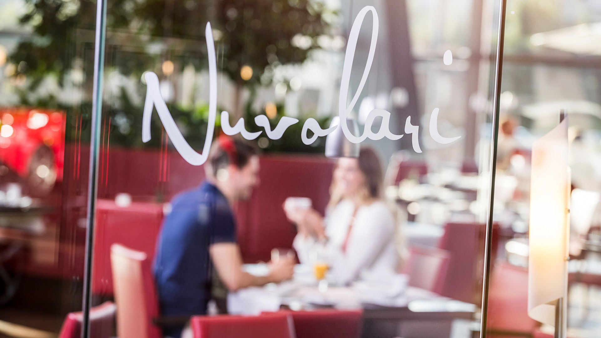 Entrance to Restaurant Nuvolari, with a couple dining at a table in the blurred background.