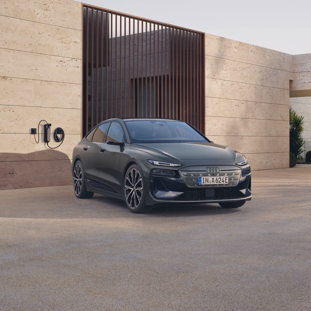 A parked Audi electric vehicle, left side visible to us, and a man walking away to the left