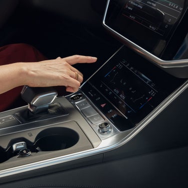 A person's hand adjusting settings on a car's touchscreen infotainment system.