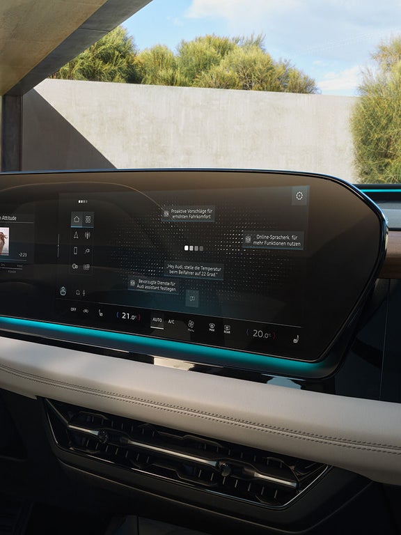 Detailansicht des durchgehenden Audi Bildschirms im Cockpit mit Navigation, Medien und Klimaeinstellungen und blauer Ambientebeleuchtung.